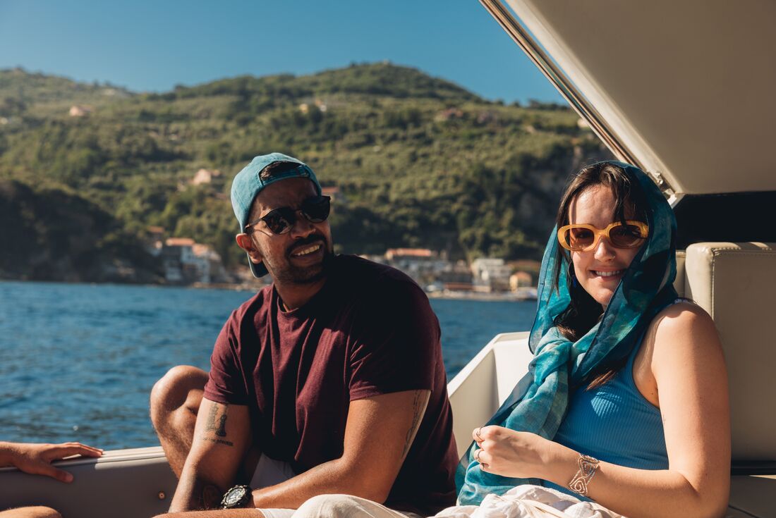 Two travellers smiling as they take a boat ride to Capri on a sunny day, Italy