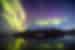 Yellow green and magenta waves of iridescent northern lights undulate over the Greenland landscape at twilight