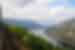 A train rides a high ridge along the Otenfjord with a forest below and mountains looming beyond