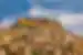 City of Mardin with ancient minarets and buildings climbs a hill to towering stone top with hawk flying in Turkey